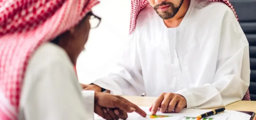 ISO consultant discussing certification documents with business client in Oman office